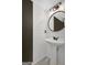 Modern bathroom with black framed round mirror, a pedestal sink, and stylish plank accent wall at 180 Bentley Way, Fayetteville, GA 30214