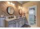 Stylish bathroom with wood accent wall, granite double vanity, and modern fixtures at 220 Edna Ruth Ln, Mcdonough, GA 30253