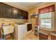 Bright laundry room with modern appliances, cabinets, sink, and large window with shutter blinds at 220 Edna Ruth Ln, Mcdonough, GA 30253
