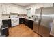 An L-shaped kitchen boasts white cabinetry, stainless steel refrigerator, and dark countertops at 4793 Davenport Nw Trce, Acworth, GA 30101
