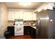 Galley kitchen featuring white cabinets, stainless steel refrigerator, and hardwood floors at 4793 Davenport Nw Trce, Acworth, GA 30101