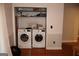 Laundry area with a side-by-side pair of modern washing machines and functional storage shelves above at 4793 Davenport Nw Trce, Acworth, GA 30101