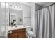 This bathroom has a wood vanity, single sink, a mirror, and a toilet next to a shower curtain at 189 Willowleaf Way, Sharpsburg, GA 30277
