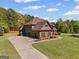 Eye-level side view of home with a long driveway and three car garage surrounded by a plush green lawn at 189 Willowleaf Way, Sharpsburg, GA 30277