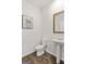 Powder room with modern pedestal sink, wood-look flooring, decorative art and framed mirror at 150 Ivy Chase Loop, Dallas, GA 30157