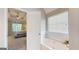 View from bedroom to soaking tub, surrounded by white tile, and window with white blinds at 30 Saint Charles Pl, Sharpsburg, GA 30277