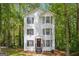 Charming three-story home with white siding, black shutters and trim surrounded by lush, mature trees at 4448 Janice Dr, Snellville, GA 30039