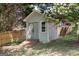 Backyard storage shed with wooden ramp and partial privacy fence and treelined background at 1212 Dayspring Trce, Lawrenceville, GA 30045
