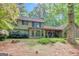 Two story home with stone and wooden exterior and shuttered windows nestled amongst mature trees at 100 Ashland Trl, Tyrone, GA 30290