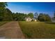 Charming home with neutral siding, dark shutters, and a long driveway surrounded by lush greenery under a clear blue sky at 110 Tamarack Trl, Mcdonough, GA 30252