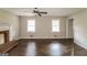 Spacious living room with hardwood floors, two windows, a ceiling fan, and a decorative fireplace at 6024 S Deshon Ct, Lithonia, GA 30058