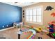 Cheerful bedroom with a vibrant blue accent wall, playroom area, and carpeted floor, perfect for a  at 109 Lighthorse Blvd, Mcdonough, GA 30252