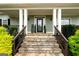 Inviting front porch featuring stone steps, white columns, and decorative plants, creating a warm welcome at 109 Lighthorse Blvd, Mcdonough, GA 30252