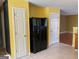 This kitchen shows a black refrigerator, bright yellow walls, and tile flooring at 1028 Field View Dr, Mcdonough, GA 30253