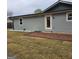 Side view of home with exterior backdoor, brick patio, grey siding, and dormant grass yard at 487 Eastside Dr, Dacula, GA 30019