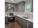 A modern kitchen features grey cabinets, stainless steel appliances, a mosaic backsplash, and wood flooring at 487 Eastside Dr, Dacula, GA 30019