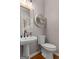 Stylish powder room with a pedestal sink, decorative mirror, and wooden floors at 216 Southwick Ln, Peachtree City, GA 30269