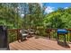A back deck with wooden flooring, chairs, and a grill surrounded by lush trees at 803 Baugh Springs Ln, Lawrenceville, GA 30044
