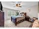 Cozy bedroom with a large bed, a ceiling fan, and a sunlit window with green plants at 803 Baugh Springs Ln, Lawrenceville, GA 30044