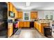 Kitchen with natural wood cabinets, black appliances, and granite countertops at 803 Baugh Springs Ln, Lawrenceville, GA 30044