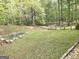 Spacious backyard with lush green grass, mature trees, rock border, wooden fence and gate at 64 Shadow Ct, Palmetto, GA 30268