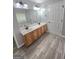 Bathroom featuring double sinks with wood vanity and wood-look gray tile floors at 64 Shadow Ct, Palmetto, GA 30268