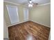 This bedroom includes hardwood floors, neutral paint, ceiling fan, and bright light from two large windows at 64 Shadow Ct, Palmetto, GA 30268