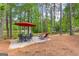 Cozy backyard patio setup with dining and lounge seating, shaded by a large red umbrella and trees at 226 Le Paradis Blvd, Sharpsburg, GA 30277