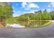 A serene pond surrounded by lush greenery reflects the clear blue sky on a sunny day at 226 Le Paradis Blvd, Sharpsburg, GA 30277