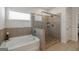 Elegant bathroom featuring a soaking tub, a glass-enclosed shower, and tiled floors at 7435 Ansley Park Way, Cumming, GA 30028