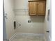 Simple laundry room with neutral tile flooring and some overhead storage at 30 Scouts Ridge Dr, Covington, GA 30016