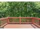 Outdoor deck with painted wood flooring and railing overlooking a wooded area at 462 Chase Marion Way, Mcdonough, GA 30253
