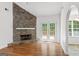Bright living room with hardwood floors, stone fireplace, and access to the outdoor space through double doors at 462 Chase Marion Way, Mcdonough, GA 30253