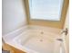 Close up on a built in bathtub in a bright bathroom with a window above it at 11224 Aliyah Dr, Hampton, GA 30228