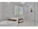 Elegant bathroom showcases a soaking tub, marble tile, glass-enclosed shower, and chandelier at 105 Suffolk Pl, Fayetteville, GA 30215
