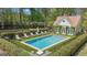 Backyard in-ground swimming pool and pool house surrounded by lush landscaping and a black fence at 105 Suffolk Pl, Fayetteville, GA 30215