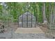 View of the greenhouse featuring glass walls and wood flooring in a wooded yard at 135 Adams Park Dr, Fayetteville, GA 30214