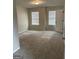 Spacious bedroom with neutral carpet, two bright windows, and a white door at 495 Mcgiboney Ln, Covington, GA 30016