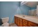 Bathroom with blue walls, vanity with sink, large mirror, toilet, and shower with sliding glass door at 3341 Deer Hollow Sw Trl, Conyers, GA 30094