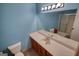 Bathroom features blue walls, vanity with sink, toilet, shower with sliding glass door, and large mirror at 3341 Deer Hollow Sw Trl, Conyers, GA 30094