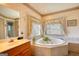 Well-lit bathroom with jacuzzi tub, neutral tile, and double vanity at 3341 Deer Hollow Sw Trl, Conyers, GA 30094