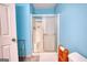 Close-up of shower with sliding glass door, blue walls, and white fixtures in bathroom at 3341 Deer Hollow Sw Trl, Conyers, GA 30094