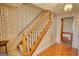 Classic staircase with wooden banister and carpeted steps with decorative wallpaper at 3341 Deer Hollow Sw Trl, Conyers, GA 30094