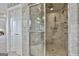 Marble tiled shower has a glass enclosure, multiple shower heads, and a built-in bench at 780 Birkdale Dr, Fayetteville, GA 30215