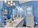 A blue bathroom with double sinks, a large mirror, and vanity lighting at 4735 Rabbit Farm Rd, Loganville, GA 30052