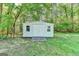 Exterior of the white storage shed with double doors and windows on either side, nestled among lush trees at 4735 Rabbit Farm Rd, Loganville, GA 30052
