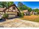Tudor-style home with garage and driveway, complemented by green grass and manicured bushes at 335 Jeff Davis Pl, Fayetteville, GA 30214