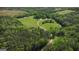 High-angle aerial displays the property's vast scale, blending open fields with dense, mature woodlands at 201 Little New York Rd, Carrollton, GA 30116