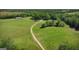 Sweeping aerial shot captures a vast, idyllic property with lush pastures and a winding gravel driveway at 201 Little New York Rd, Carrollton, GA 30116