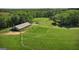 Aerial view showcasing a large grassy lot, with outbuilding, and serene, wooded surroundings at 201 Little New York Rd, Carrollton, GA 30116